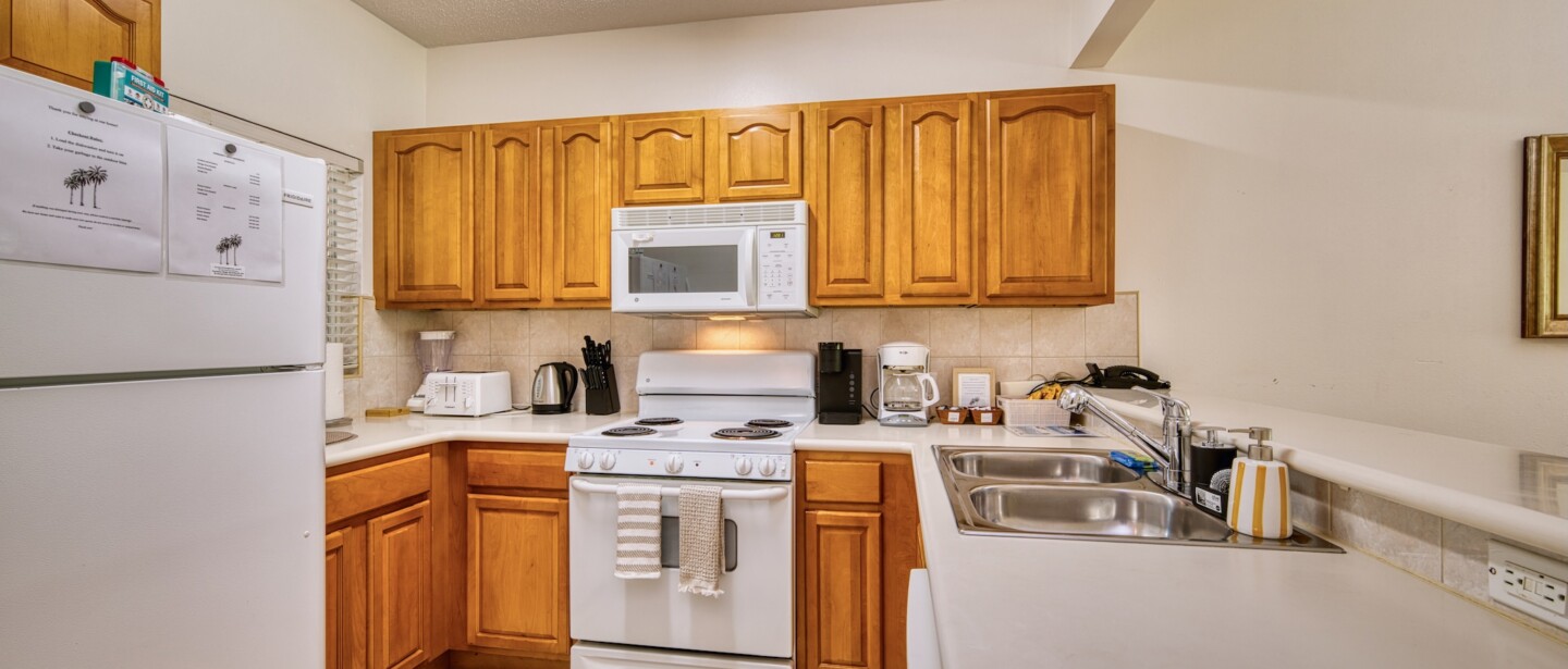 Bright full kitchen with coffee maker, ample counters, and warm wood cabinets
