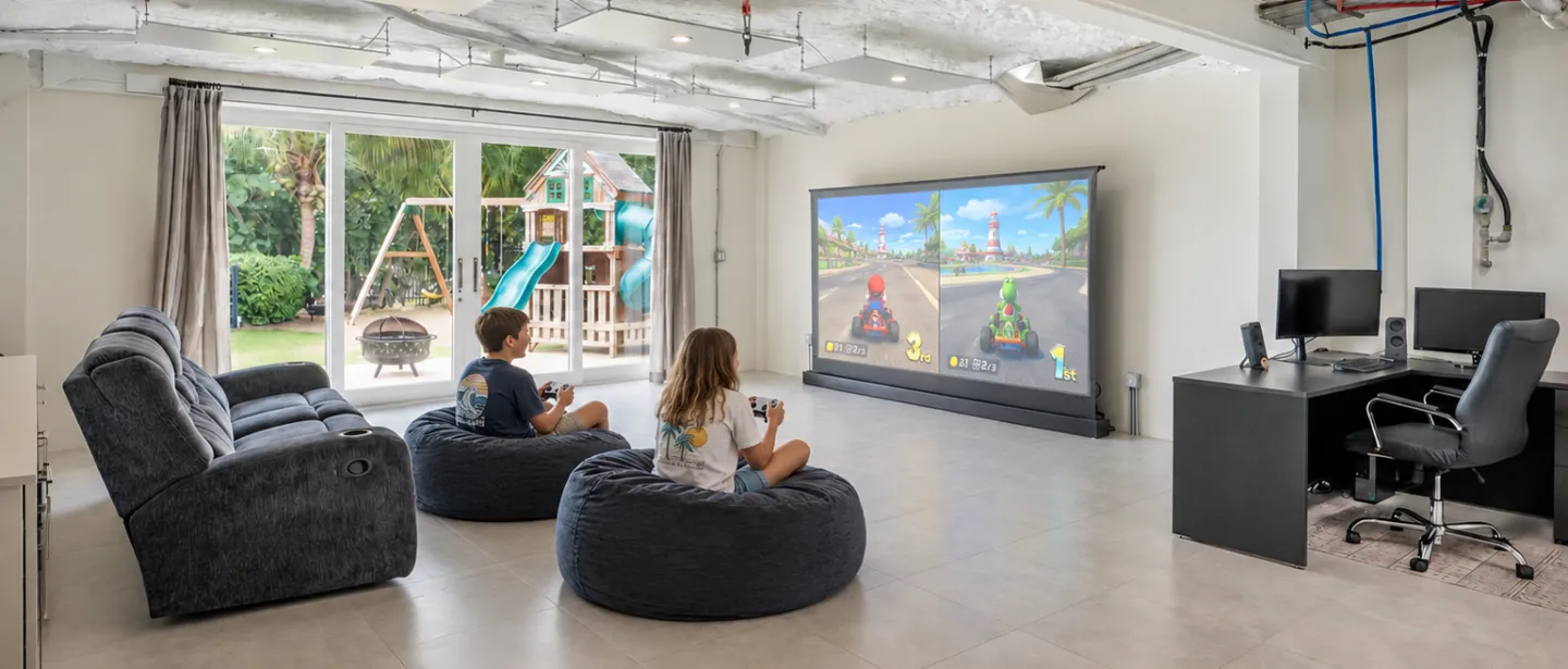 Spacious game room with projector screen, comfy seating, and backyard views.
