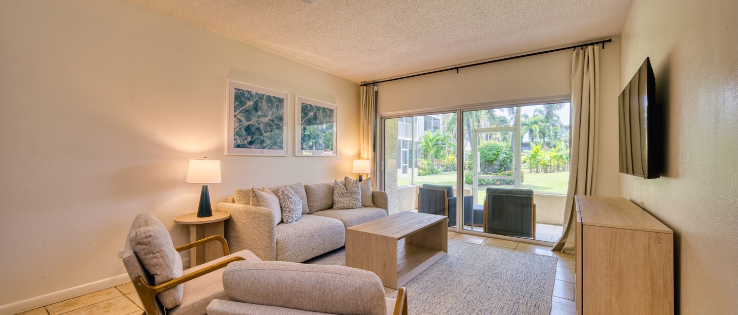 Bright living room with patio seating and tropical garden views