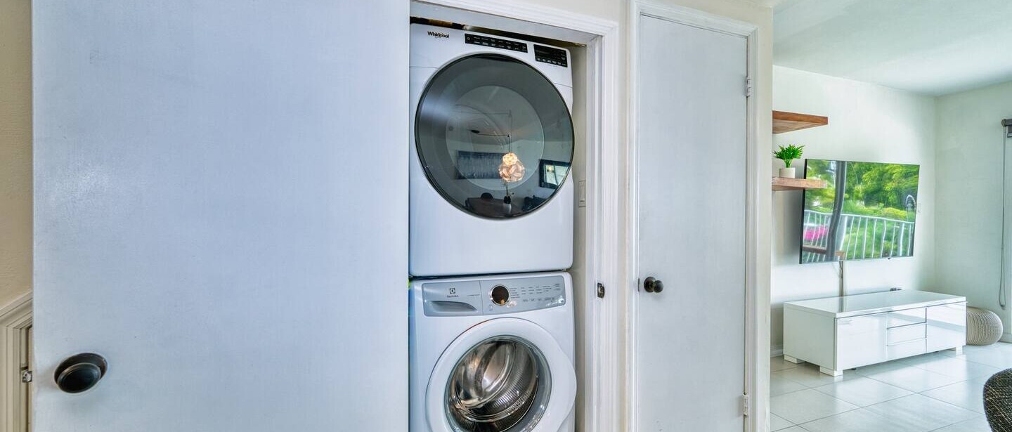Full laundry with large washer and dryer in cupboard