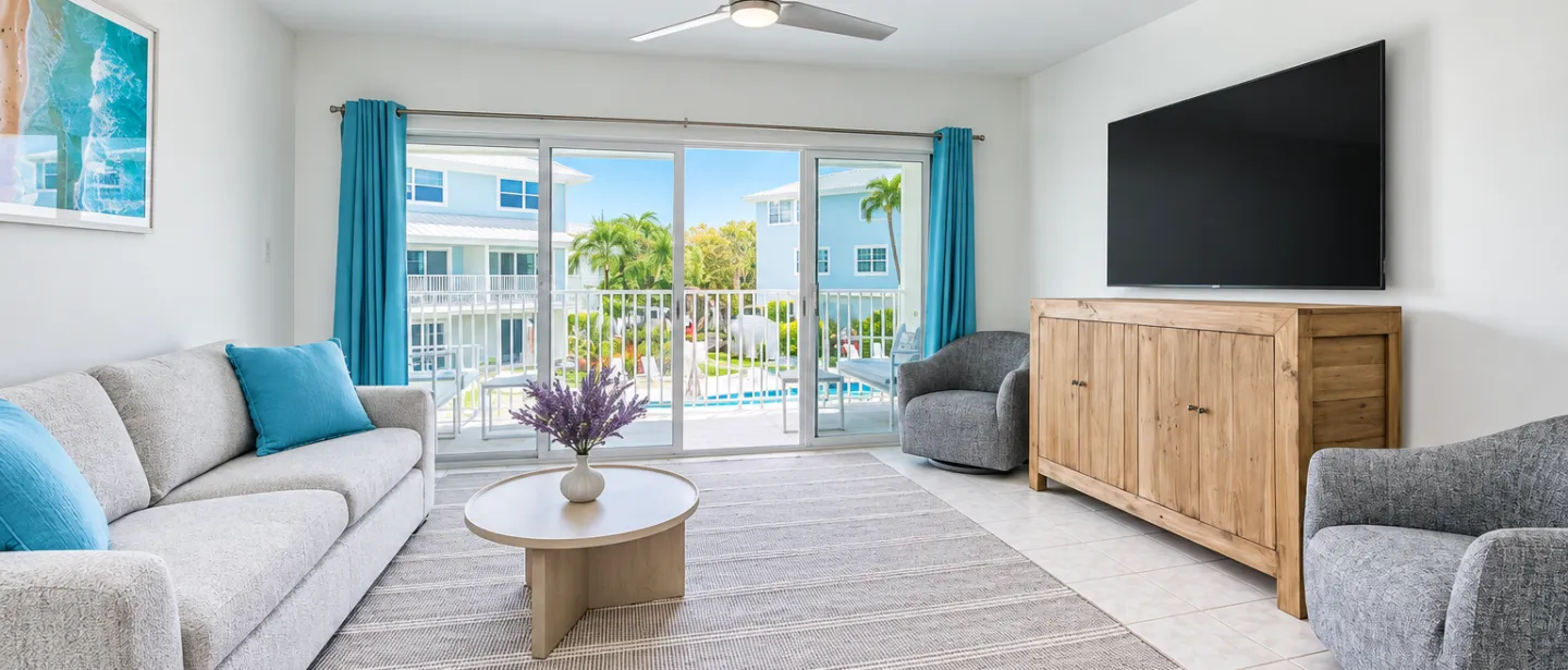 Bright coastal living room with balcony, pool views, and large TV
