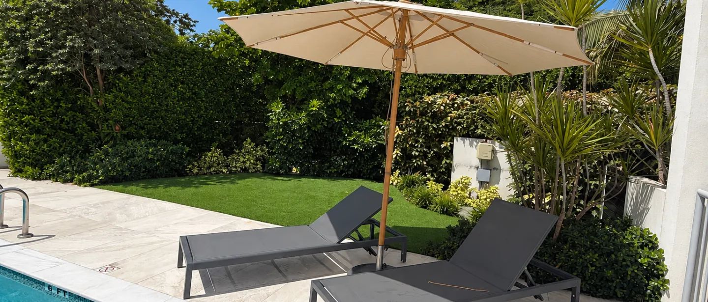 Sunny private poolside loungers with umbrella and lush tropical garden