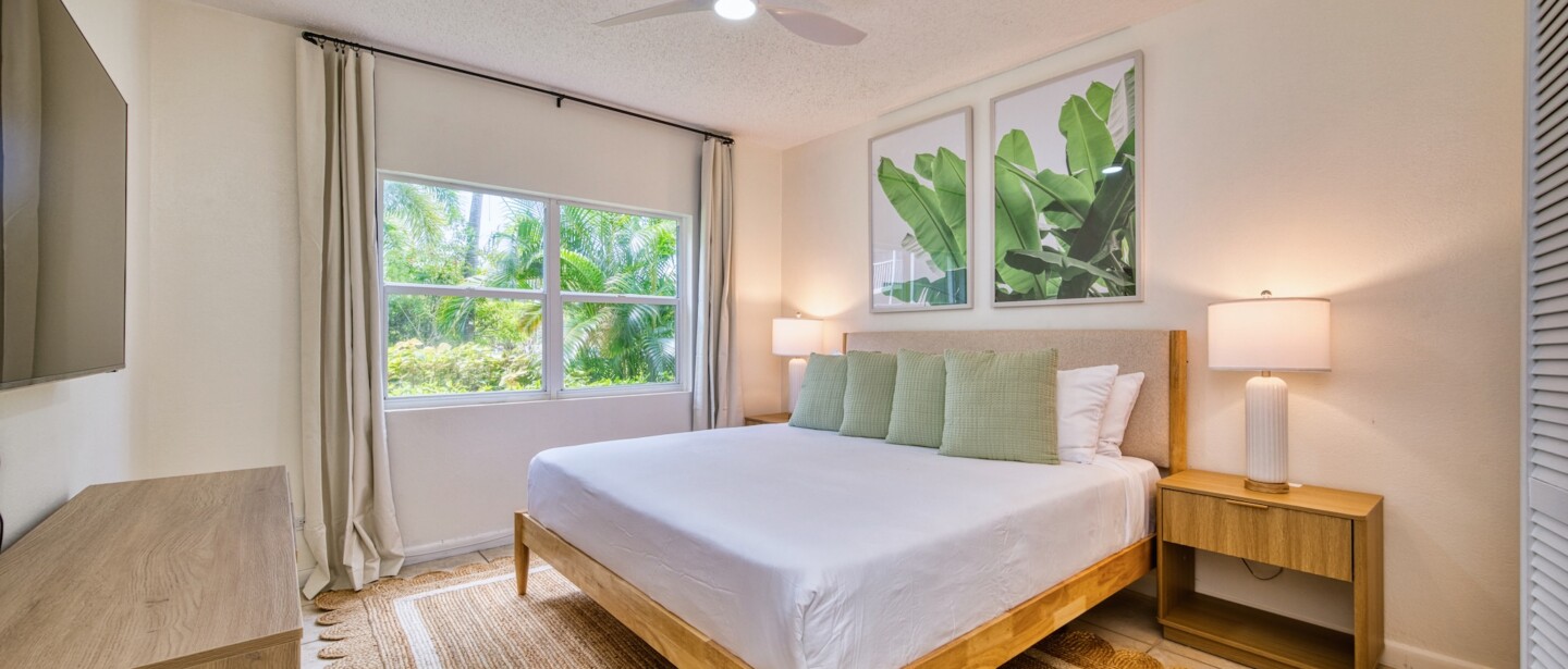 Bright tropical bedroom with king bed and lush garden views