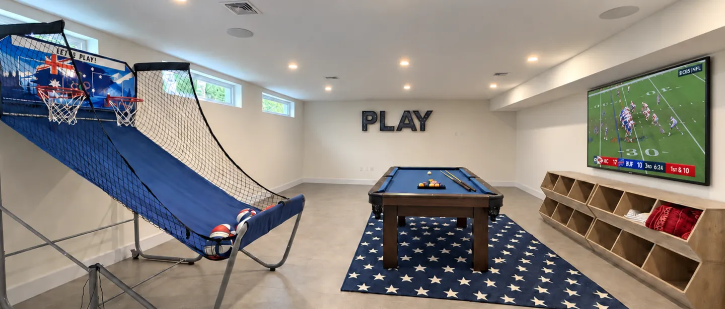 Spacious game room with pool table, hoops, and big-screen TV
