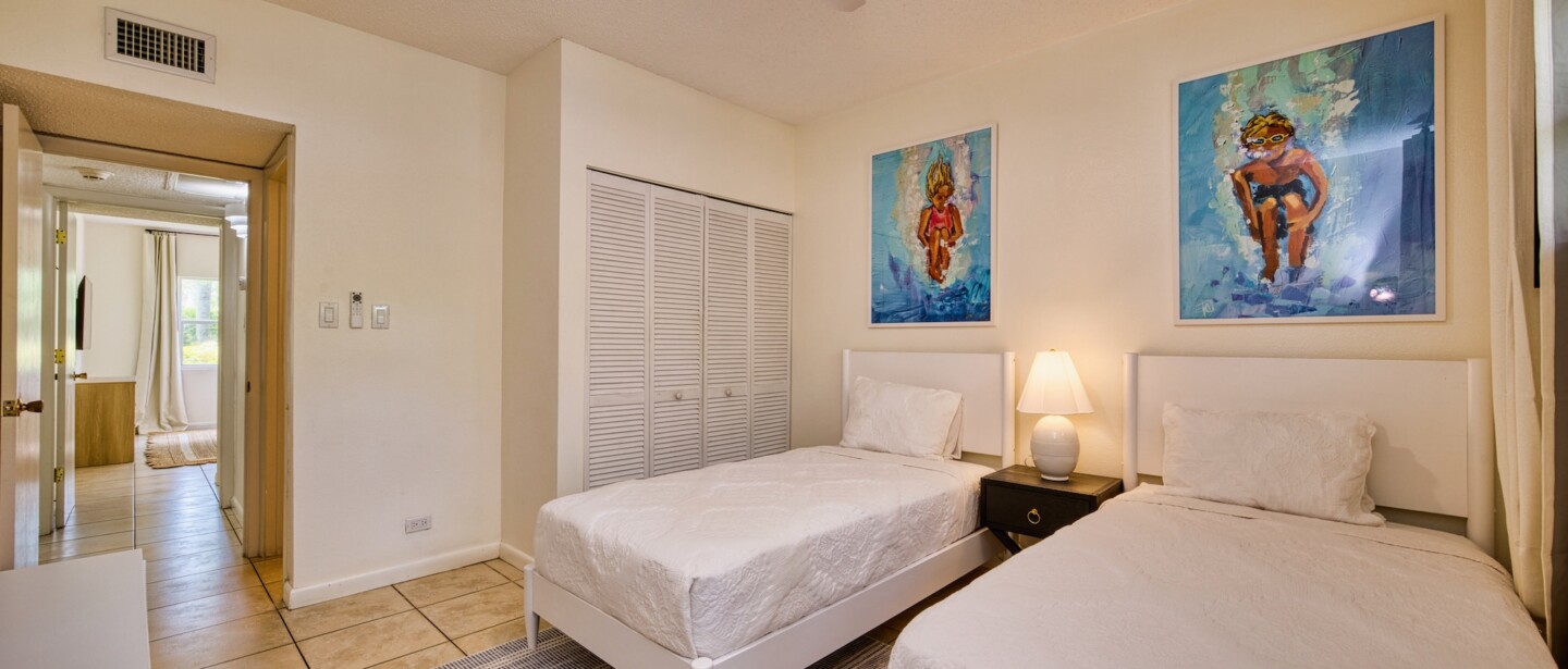 Bright twin bedroom with coastal art, closet space, and airy comfort