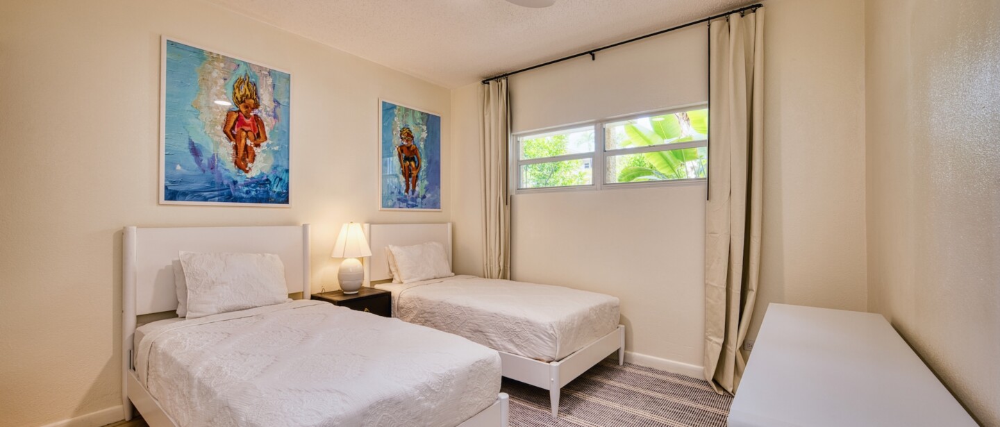 Bright twin bedroom with coastal art, soft light, and a peaceful feel