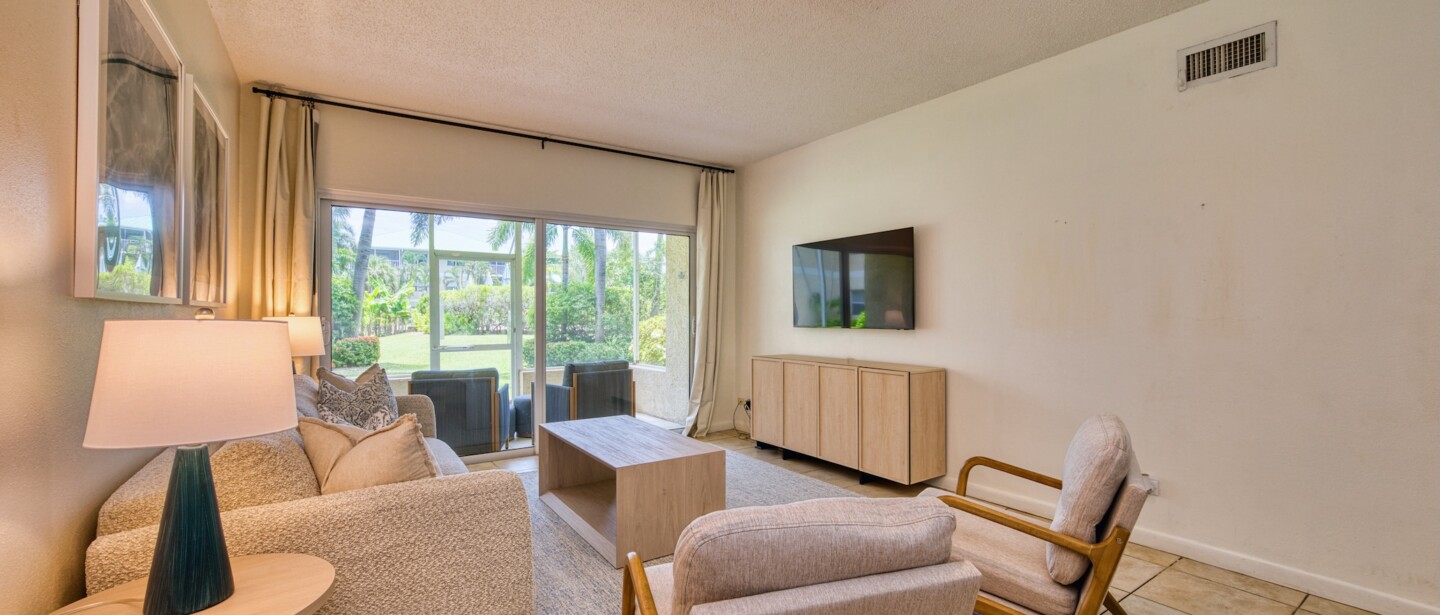 Bright living room with patio access, comfy seating, and garden views